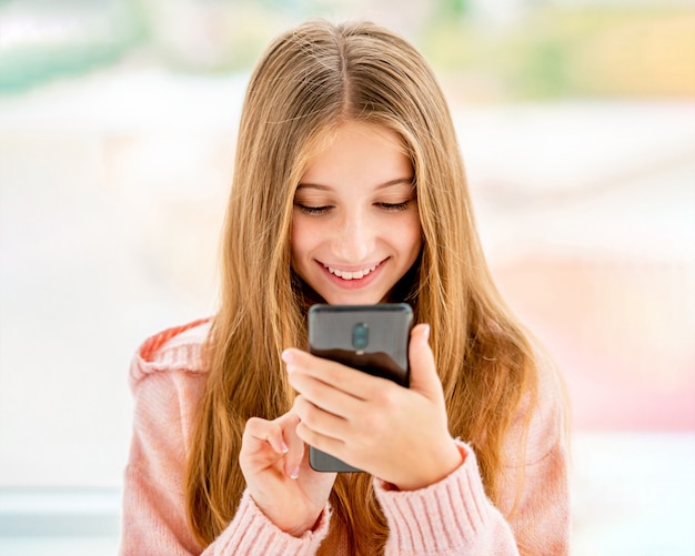 Adolescente, escribiendo en el teléfono móvil