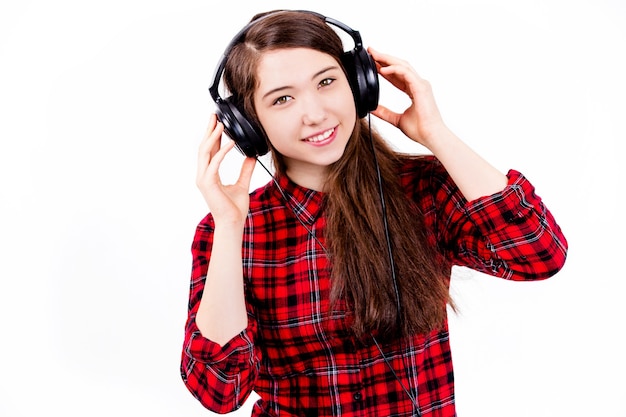 Adolescente escucha música en el estudio sobre una pared blanca