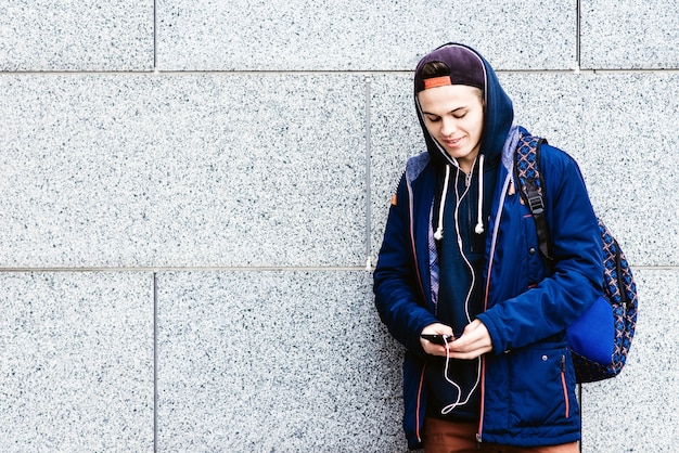 Adolescente escuchando música y utilizando teléfono en entorno urbano