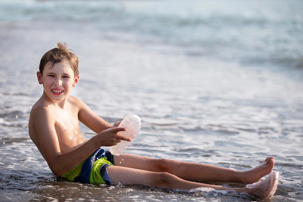 Un adolescente está sentado en la orilla del mar.