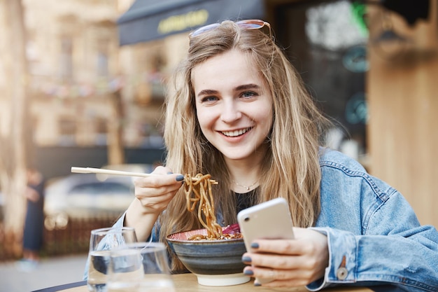 Adolescente con estilo no puede dejar el teléfono inteligente incluso mientras come