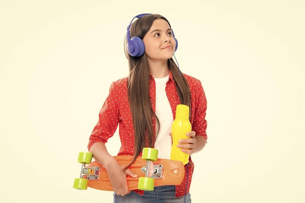 Adolescente estudante com garrafa de água de skate e fones de ouvido em estúdio isolado fundo primavera