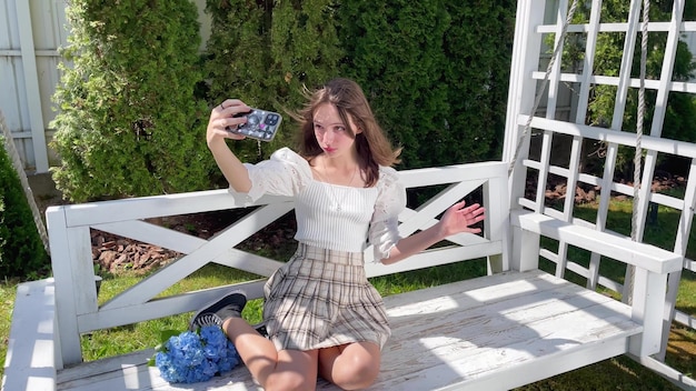 Adolescente fazendo selfie em seu telefone no jardim em swing