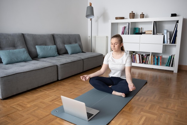 Adolescente fazendo um curso de ioga virtual em casa