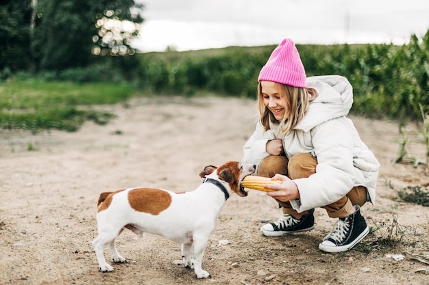 Una adolescente feliz abrazando y alimentando a su perro Jack Russell Terrier en un campo