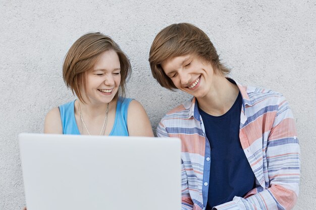 Adolescente feliz, com cabelos cortados, vestida de vestido azul e sua amiga com penteado moderno usando camisa