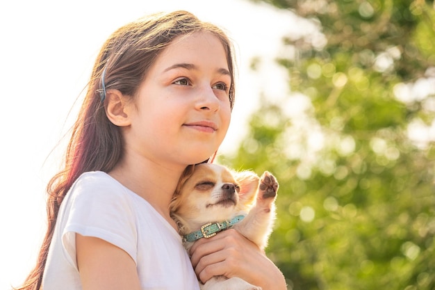 Adolescente feliz com um cachorro Chihuahua branco com manchas vermelhas. Menina em uma camiseta branca.