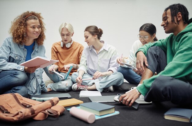 Adolescente feliz con cuaderno mirando a su novio afroamericano