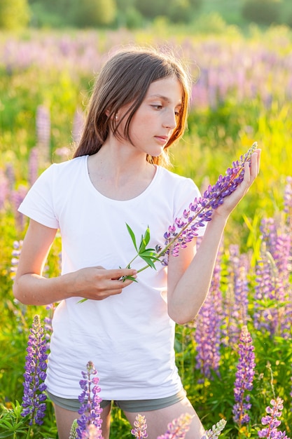 Adolescente feliz descansando no campo de verão com flores silvestres desabrochando