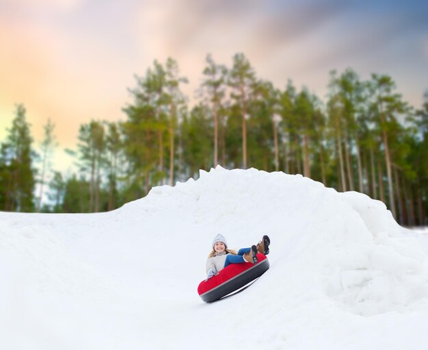 Foto una adolescente feliz deslizándose por la colina en un tubo de nieve