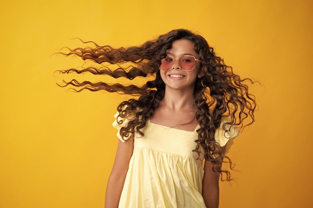 Foto adolescente feliz emociones positivas y sonrientes de niña adolescente retrato de adolescente con cabello de movimiento loco niño adolescente joven con cabello que fluye morena adolescente niña revoloteando cabello en movimiento aislado en amarillo