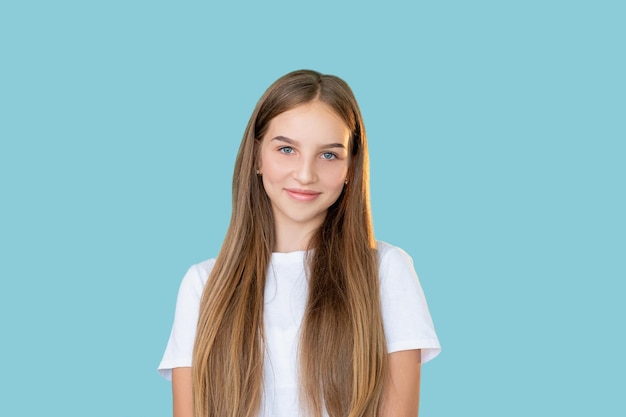 Adolescente feliz Estilo de vida da juventude Atitude positiva Inspiração de motivação Retrato de menina alegre e satisfeita em camiseta branca olhando para a câmera sorrindo isolada no fundo azul do espaço da cópia