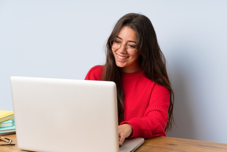 Foto adolescente feliz estudiante chica estudiando en una mesa