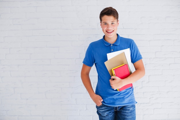 Adolescente feliz con libros mirando a la cámara