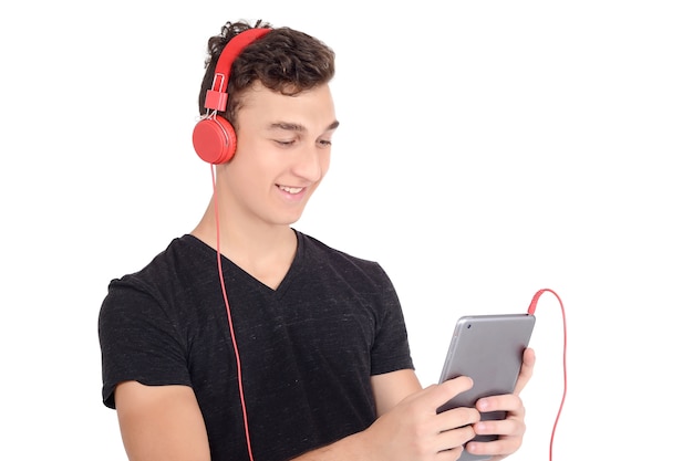 Adolescente feliz que usa la tableta con los auriculares