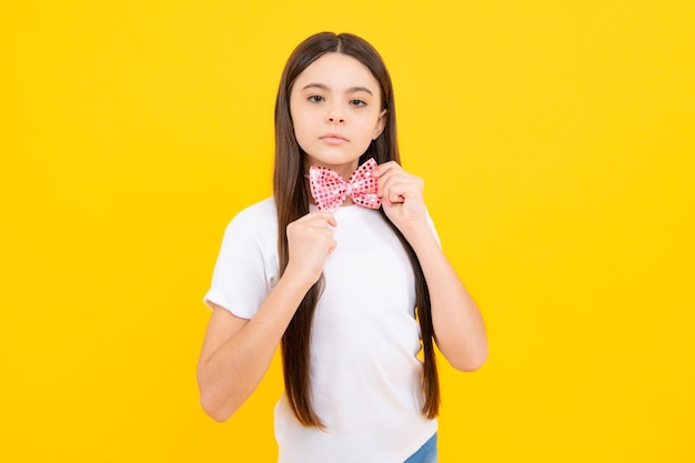 Adolescente feliz retrato de niña sonriente en camiseta con corbatín aislado sobre fondo amarillo