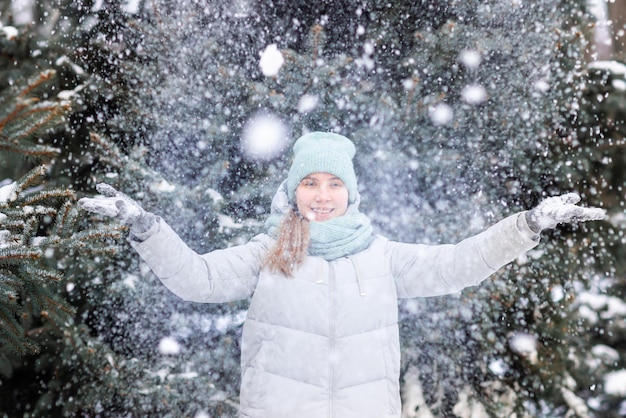 Adolescente feliz se divertindo brincando com bolas de neve, prontas para jogar a bola de neve.