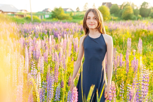 Adolescente feliz sonriendo al aire libre. Hermosa joven adolescente descansando en el campo de verano con flores silvestres en flor fondo verde