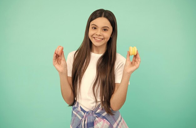 Una adolescente feliz sostiene una confitería de galletas de macarrones o macarons franceses