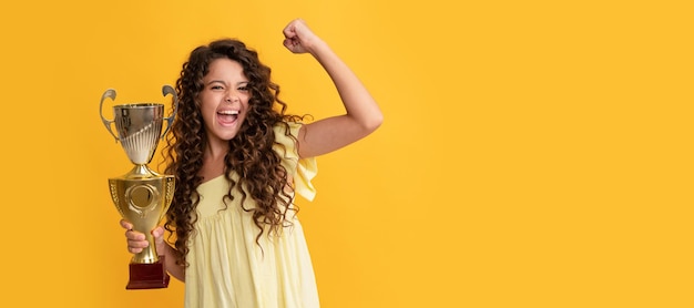 Una adolescente feliz sostiene el premio al logro de la copa de oro celebrando el éxito y la victoria Afiche horizontal