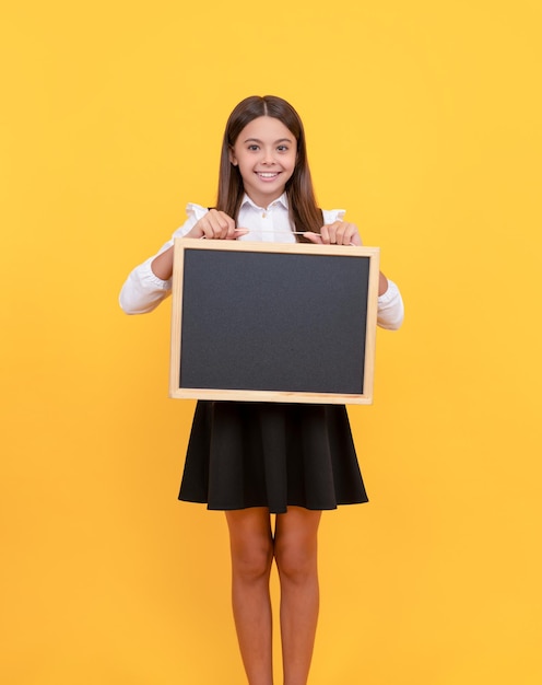 Una adolescente feliz sostiene una publicidad infantil en la pizarra de regreso a la escuela presentando información novedosa
