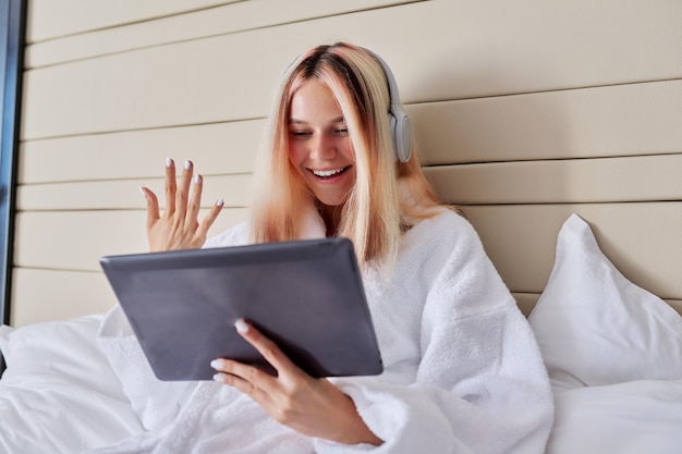 Adolescente femenina sonriente en auriculares con tableta digital