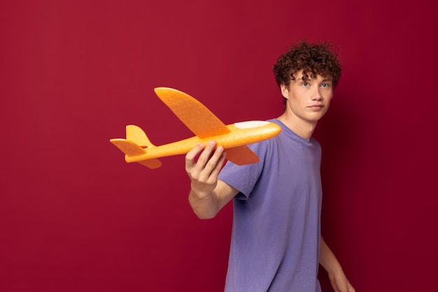 Adolescente con fondo rojo de entretenimiento de avión de juguete inalterado