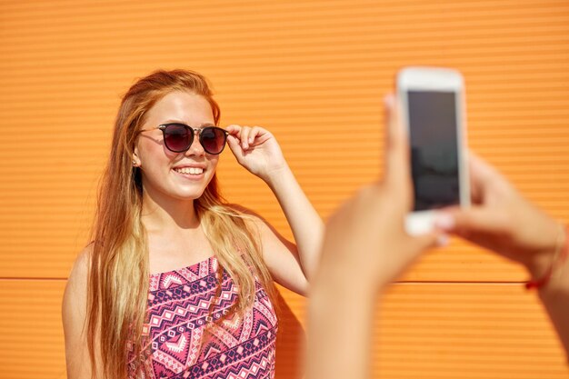 una adolescente fotografiando a una amiga con su teléfono inteligente
