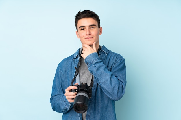 Adolescente fotógrafo hombre aislado en la pared azul riendo