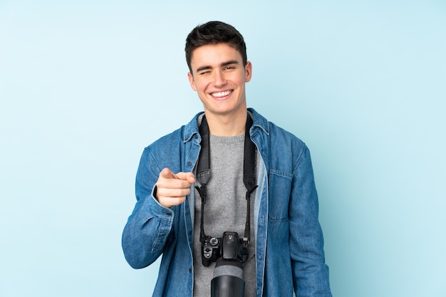 Foto adolescente fotógrafo hombre aislado en la pared azul señala con el dedo