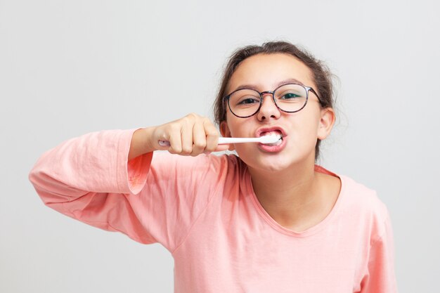 Foto una adolescente con gafas se cepilla los dientes