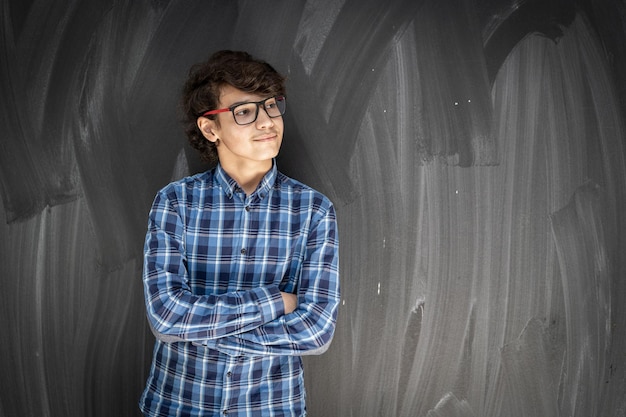 Adolescente con gafas delante de la pizarra del aula