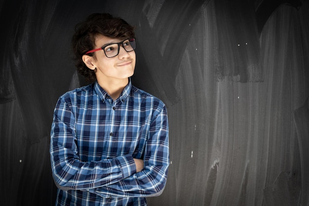 Adolescente con gafas delante de la pizarra del aula