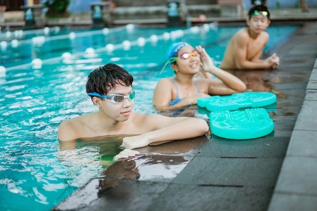 Un adolescente en gafas de natación mientras está de pie en la piscina