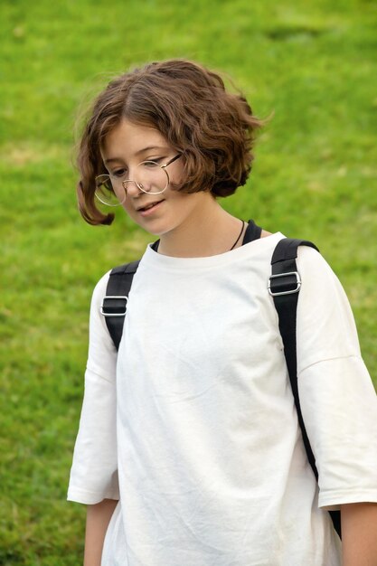 Adolescente en gafas con pelo rizado y camiseta blanca