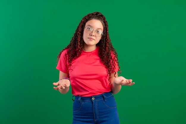 Adolescente con gafas en poses divertidas en una foto de estudio con un fondo verde ideal para recortar