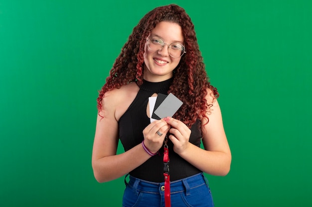 Adolescente con gafas en poses divertidas en una foto de estudio con un fondo verde ideal para recortar