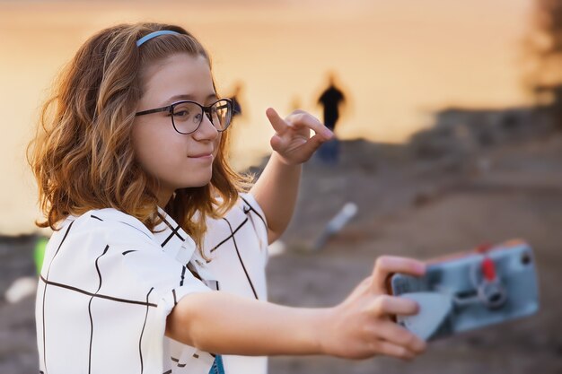 Adolescente con gafas toma selfie