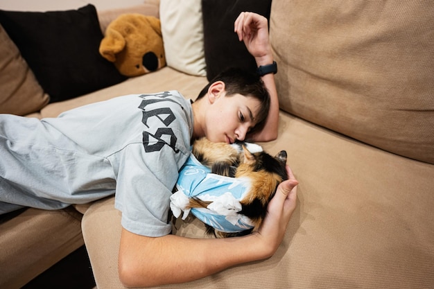 Adolescente con gato dormido en un vendaje después de la cirugía Cuidado de una mascota después de la esterilización de la operación cavitaria