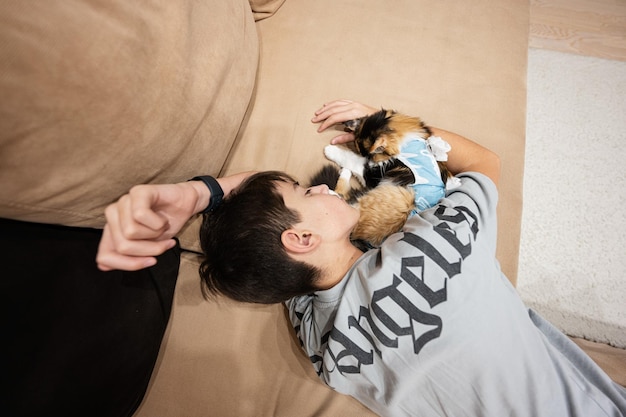 Adolescente con gato dormido en un vendaje después de la cirugía Cuidado de una mascota después de la esterilización de la operación cavitaria