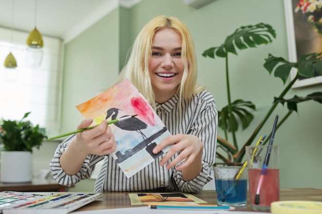 Adolescente grabando una lección de dibujo en video viendo y mostrando técnicas de pintura a la cámara