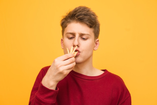 Adolescente gracioso come un puñado de papas fritas en un amarillo