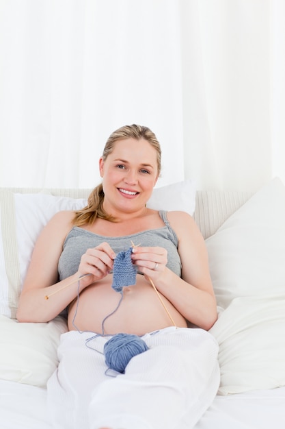 Adolescente grávida adorável tricotando na cama