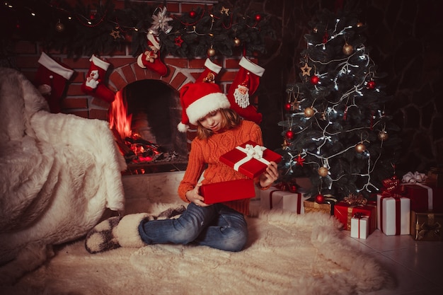 Adolescente en la habitación decorada de Navidad abre una caja de regalo