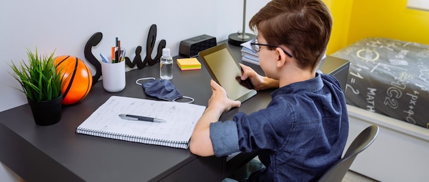 Foto adolescente haciendo la tarea con una tableta en su habitación