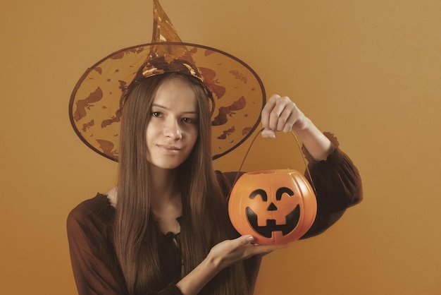 Una adolescente de Halloween vestida de bruja con una calabaza