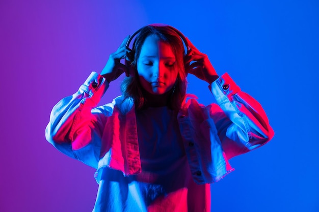 Adolescente hipster hermosa modelo de chica de moda usar auriculares con estilo Fondo de neón