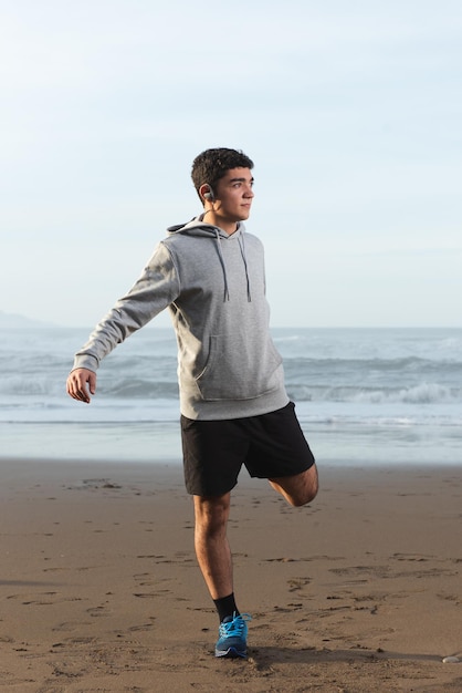 Adolescente hispana calentando antes de entrenar en la playa