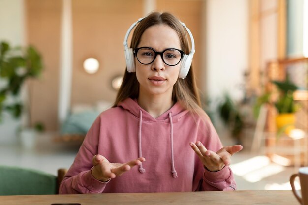 Adolescente inteligente enfocada en auriculares hablando en una computadora portátil estudiando en línea teniendo una lección en línea con un tutor