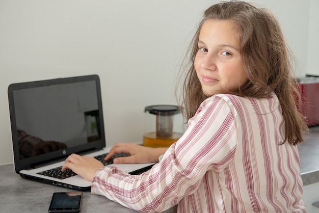 Adolescente joven que usa una computadora portátil en la mañana
